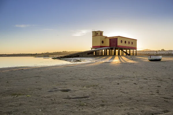 Puesta del sol y edificio histórico de la guardia vital en primer plano, en la ciudad pesquera de Fuseta, parque de conservación de Ria Formosa, Algarve . —  Fotos de Stock