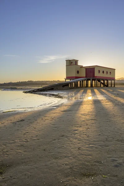 Puesta del sol y edificio histórico de la guardia vital en primer plano, en la ciudad pesquera de Fuseta, parque de conservación de Ria Formosa, Algarve . — Foto de Stock