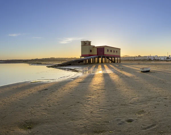 Puesta del sol y edificio histórico de la guardia vital en primer plano, en la ciudad pesquera de Fuseta, parque de conservación de Ria Formosa, Algarve . —  Fotos de Stock