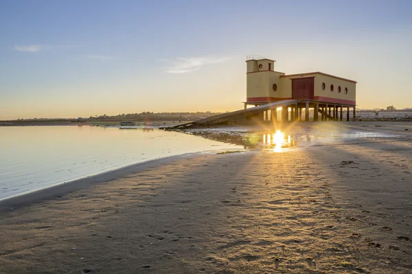 Solnedgång och historiska liv-guard byggnad i förgrunden, på Fuseta fiskeby, Ria Formosa bevarande park, Algarve. — Stockfoto