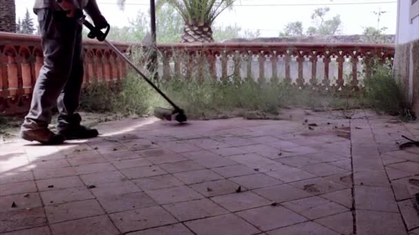 Erba stringa trimmer giardiniere, pulizia vecchio patio nel recupero edificio . — Video Stock