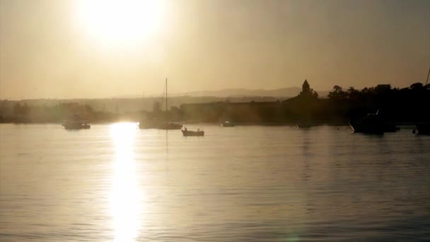 Łodzi sylwetka na zachodzie słońca, w tle portu rybackiego Quatro Aguas, widok z wyspy Tavira, rezerwat przyrody Ria Formosa. Algarve. — Wideo stockowe