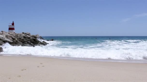 Havsutsikt över en liten fyr och folk surfing i ön Tavira, Algarve, Portugal. — Stockvideo