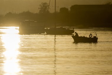 Tekneler siluet batımında, Tavira adadan, Ria Formosa doğal rezerv Quatro Aguas Balık tutma bağlantı noktası arka planda görüntüleyin. Algarve