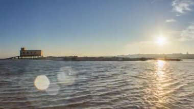 Gün batımı ve tarihi-ön planda, Fuseta balıkçı kasabası, Ria Formosa koruma Parkı, Algarve bina cankurtaran.