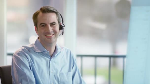 Hombre de negocios con auriculares mirando a la cámara — Vídeos de Stock