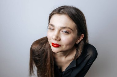 Kırmızı dudaklı güzel bir kız göz kırpıyor. Açık arkaplanda büyük bir portre