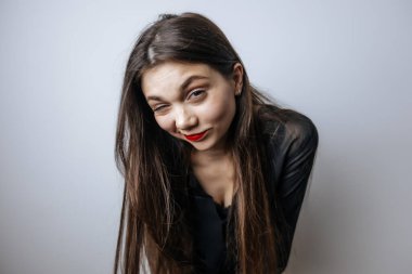 Kırmızı dudaklı güzel kız kameraya bakıyor. Açık gri arkaplanda yakın plan portresi.