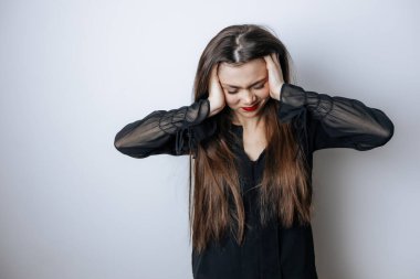 Kırmızı dudaklı bir kadın açık gri arka planda şakaklarıyla başını tutuyor.