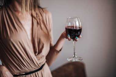 Bir kadın restoranda bir bardak kırmızı şarap tutuyor..