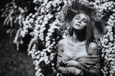 Doğada şapka ve elbise giymiş çekici bir kızın siyah beyaz portresinin aksine. Sinema tahıllarıyla, gürültüyle