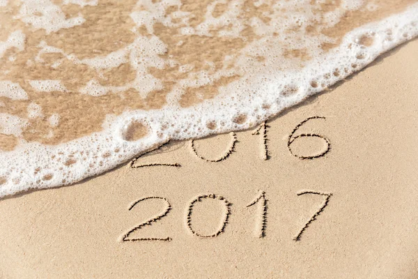 2016 2017 nápis, napsaný v mokré žlutý písek z pláže je — Stock fotografie
