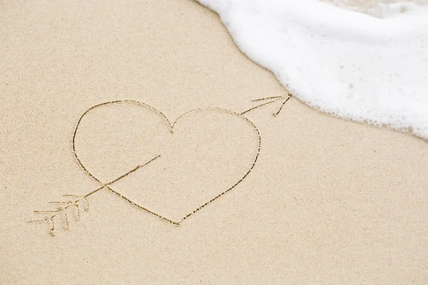 Immagine di un cuore trafitto con una freccia sulla sabbia bagnata della spiaggia — Foto Stock