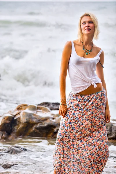 Donna bionda posa sulla riva rocciosa del mare — Foto Stock