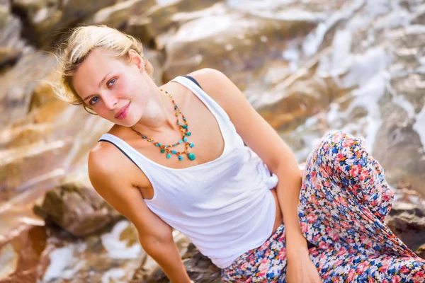 Blond kvinna poserar vid rocky havet — Stockfoto