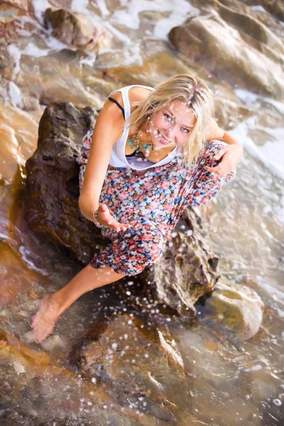 Blonde woman posing  at the rocky sea shore — Stock Photo, Image