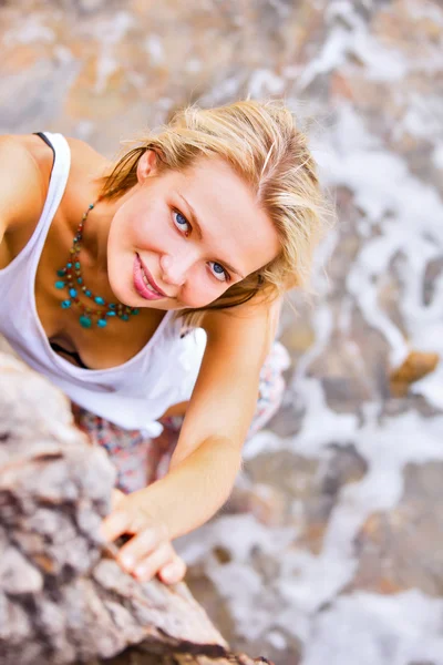 Blonde woman posing  at the rocky sea shore — Stock Photo, Image