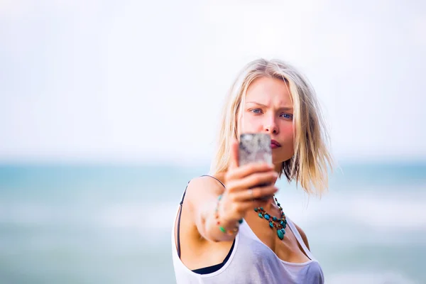 Woman taking a selfie  at the rocky sea shore. — Stock Photo, Image