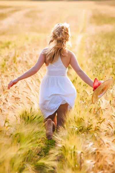 Glückliches junges blondes Mädchen im weißen Kleid mit Strohhut läuft — Stockfoto