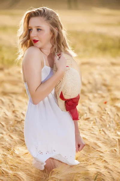 Lonely beautiful young blonde girl in white dress with straw hat — Stock Photo, Image