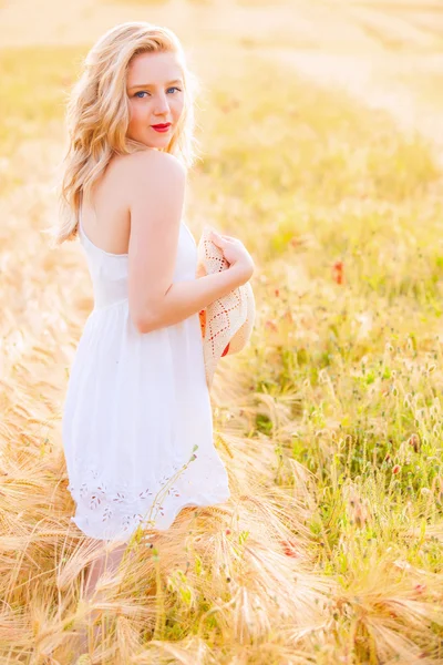 Lonely beautiful young blonde girl in white dress with straw hat — Stock Photo, Image