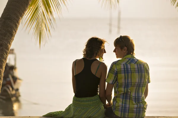 Pareja sentarse juntos bajo una palmera — Foto de Stock