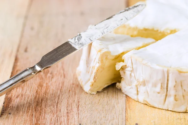 Queso Camembert con cuña cortada y cuchillo vintage sobre tabla de madera — Foto de Stock