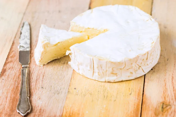 Queso Camembert con cuña cortada y cuchillo vintage sobre tabla de madera — Foto de Stock