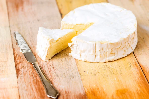 Queso Camembert con cuña cortada y cuchillo vintage sobre tabla de madera — Foto de Stock