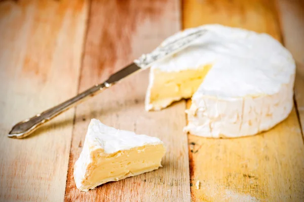 Queso Camembert con cuña cortada y cuchillo vintage sobre tabla de madera — Foto de Stock