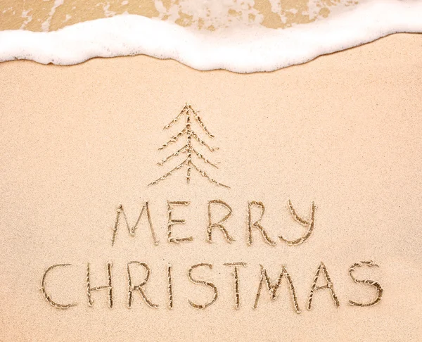 Merry Christmas written on wet sand — Stock Photo, Image