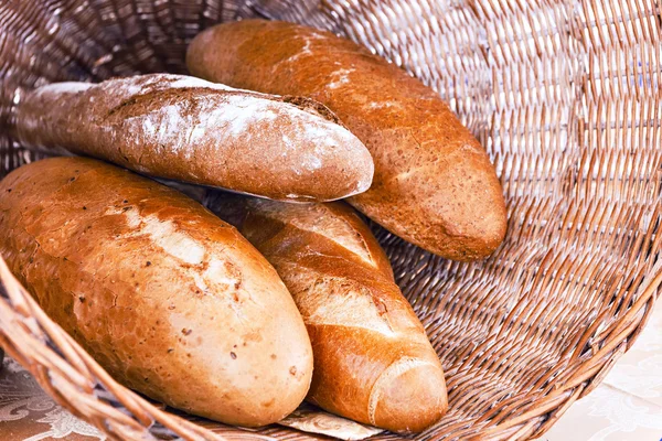 Rye and wheat bread loafs in a rustic braided basket — Stock Photo, Image