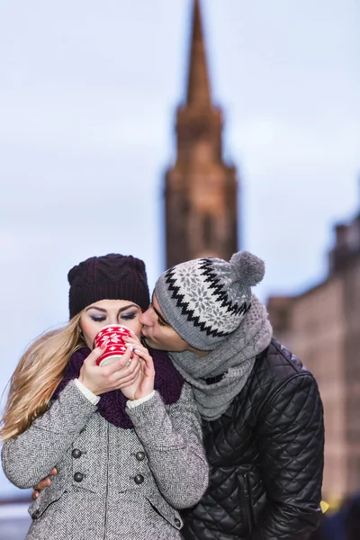 Giovane coppia innamorata che abbraccia e beve bevanda calda dalla tazza rossa — Foto Stock