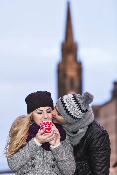 Young couple in love embracing and drinking hot drink from red cup — Stock Photo, Image