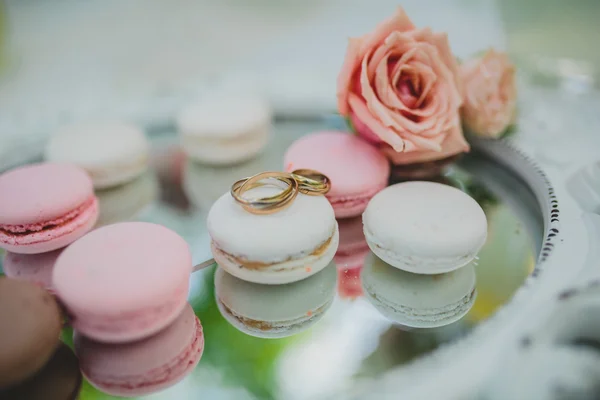 Macarrón y acostado en ella anillos de boda con fondo de espejo —  Fotos de Stock