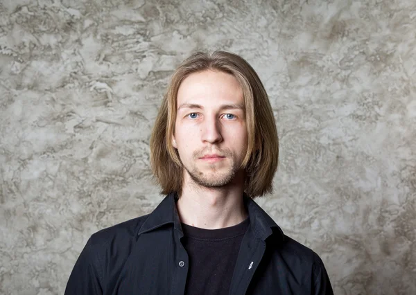 Porträtt av ung man med långa blonda hår, svart skjorta — Stockfoto
