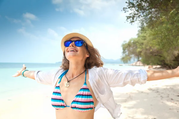 Jovem mulher bonita feliz em um chapéu e óculos de sol na costa — Fotografia de Stock