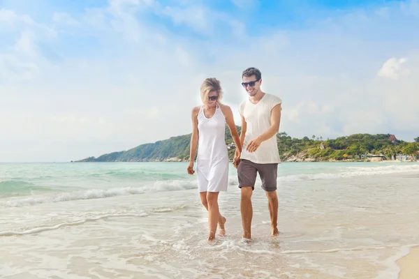 Bella giovane coppia a piedi lungo la riva di un mare tropicale — Foto Stock