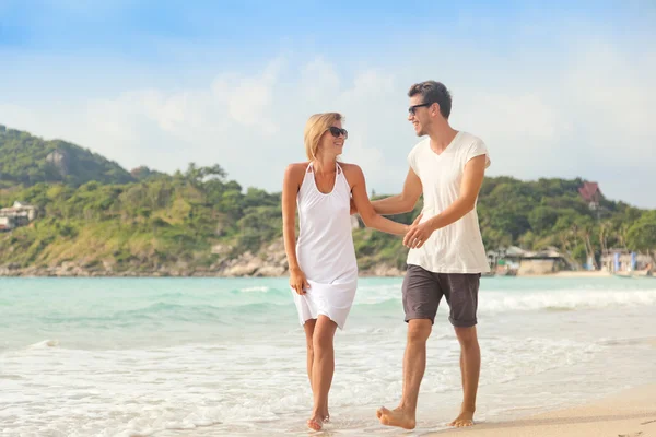 Beau jeune couple marchant le long du rivage d'une mer tropicale — Photo