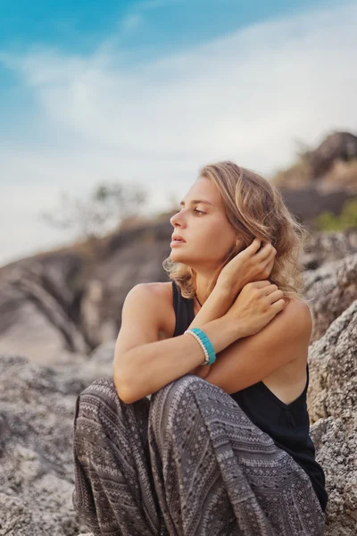 Hermosa joven sentada en las rocas, al aire libre . — Foto de Stock