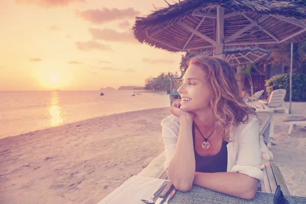 Hermosa joven sentada en el café en la playa y ver —  Fotos de Stock