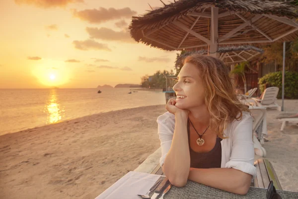 Hermosa joven sentada en el café en la playa y ver —  Fotos de Stock