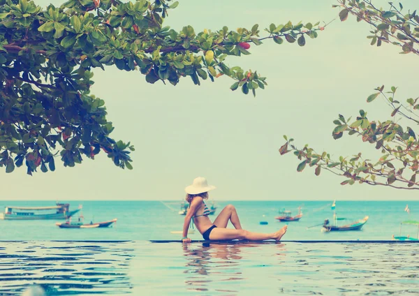 Νεαρή γυναίκα στο μπικίνι και καπέλο στην πισίνα με θέα στη θάλασσα — Φωτογραφία Αρχείου