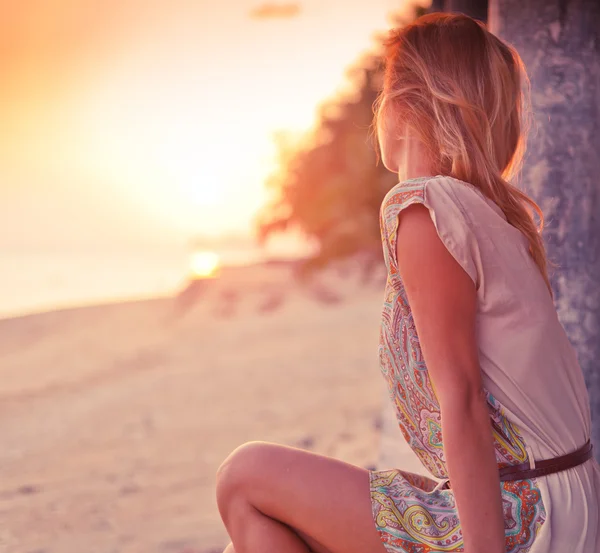 Blond kobieta na plaży oglądając zachód słońca — Zdjęcie stockowe