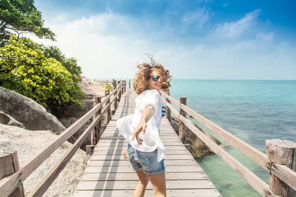 Hermosa joven corriendo a lo largo del puente contra la espalda —  Fotos de Stock