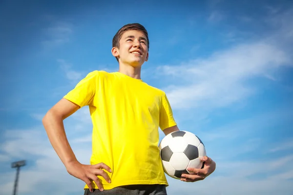 Szczęśliwy nastoletnim chłopcem z piłki nożnej na tle niebieskiego nieba — Zdjęcie stockowe