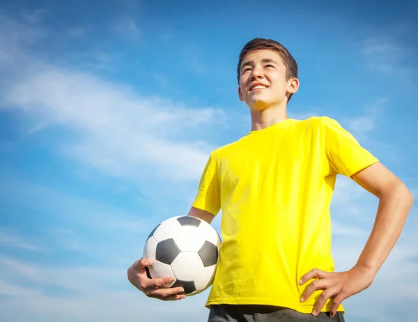 Feliz adolescente con una pelota de fútbol en un fondo de cielo azul —  Fotos de Stock