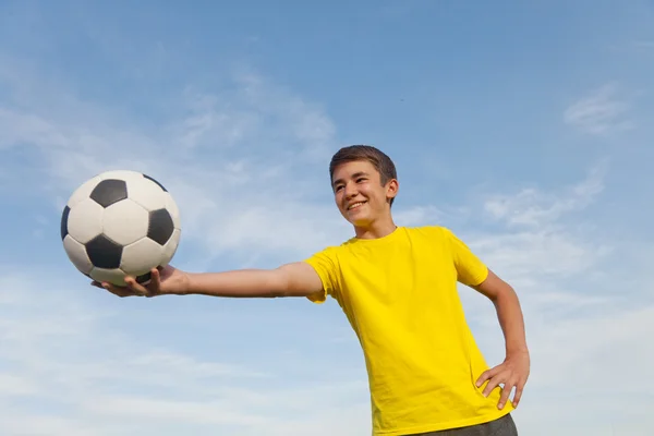 Szczęśliwy nastolatek posiada piłki nożnej w jego ręce, na tle — Zdjęcie stockowe