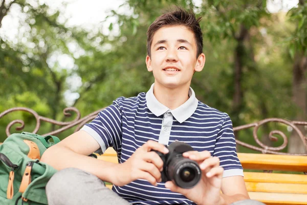 Menino adolescente feliz com uma câmera na mão, no parque de verão — Fotografia de Stock