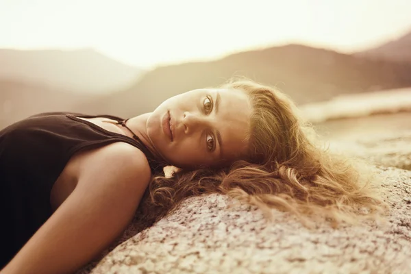 Belle jeune femme couchée sur les rochers au bord de la mer et regardant — Photo